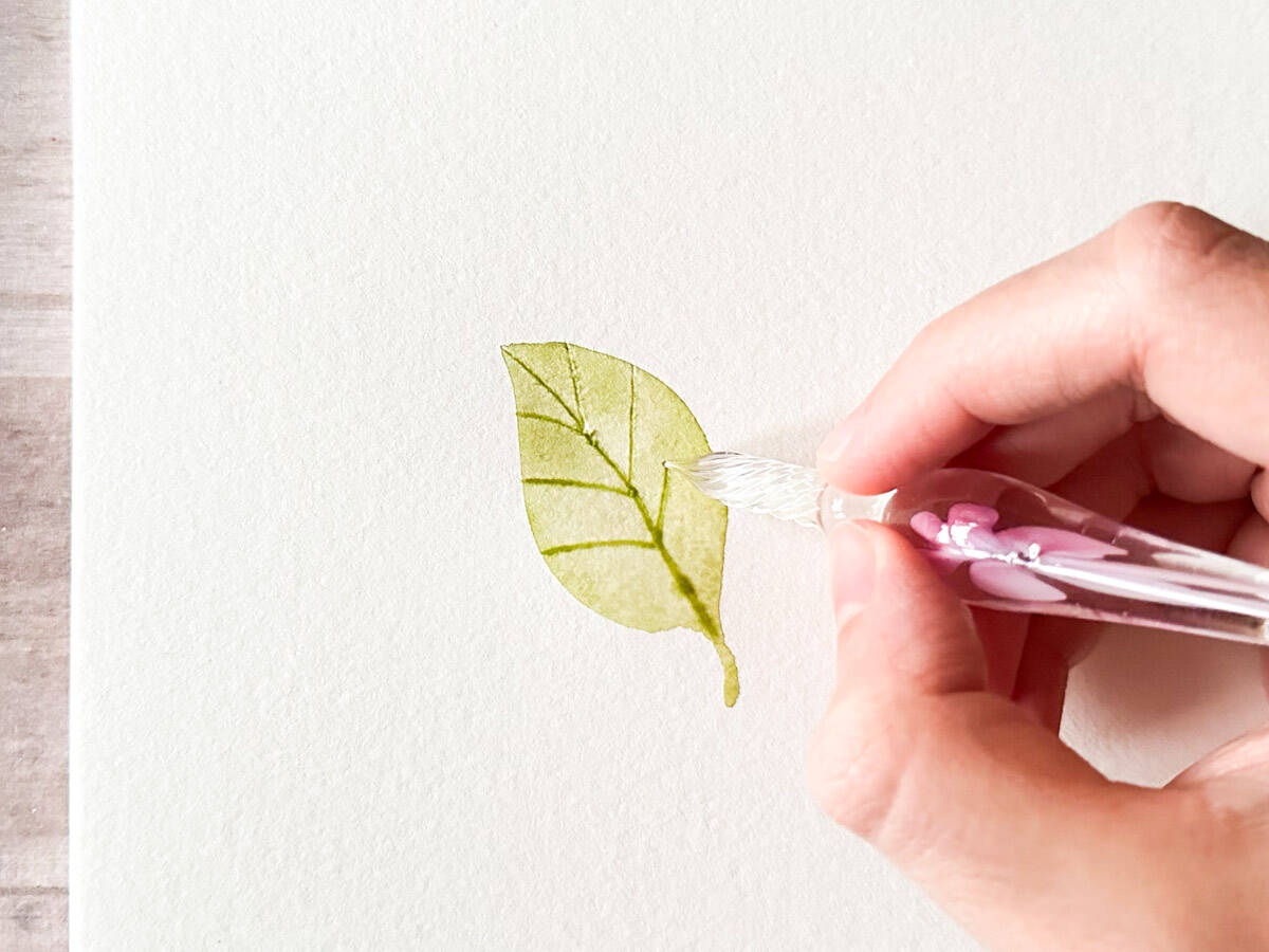 drawing leaf veins on a watercolor leaf with glass pen